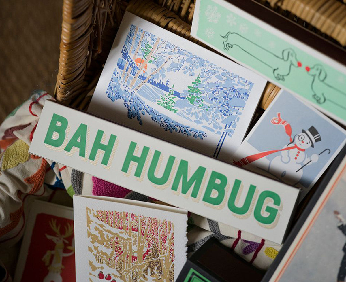 Green and gold boxed Long Matches Bah Humbug in a wicker basket with greetings cards.