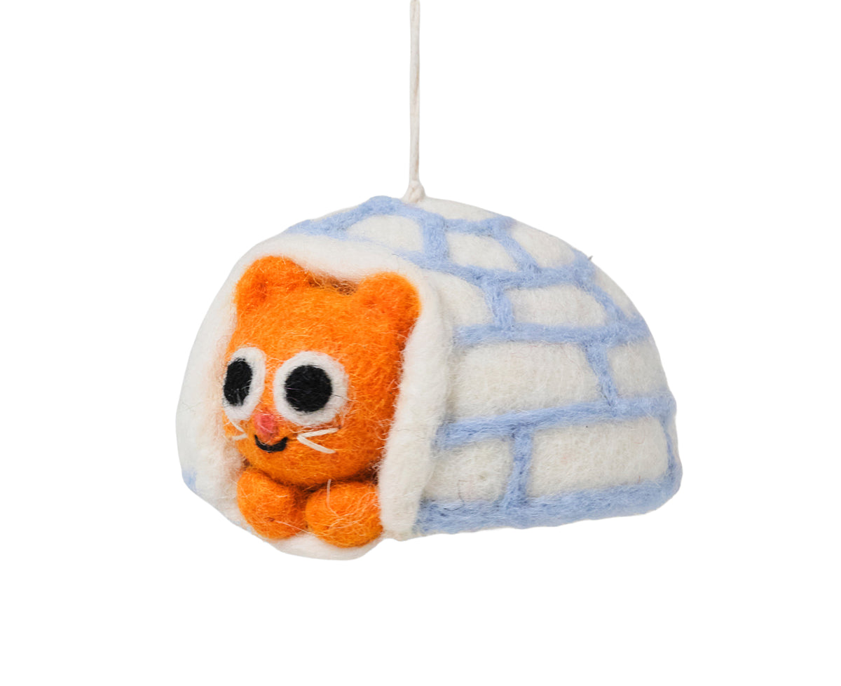 A felt hanging ornament depicting an orange kitten peeking out from a white igloo with light blue brick lines, suspended by a white string against a plain white background.