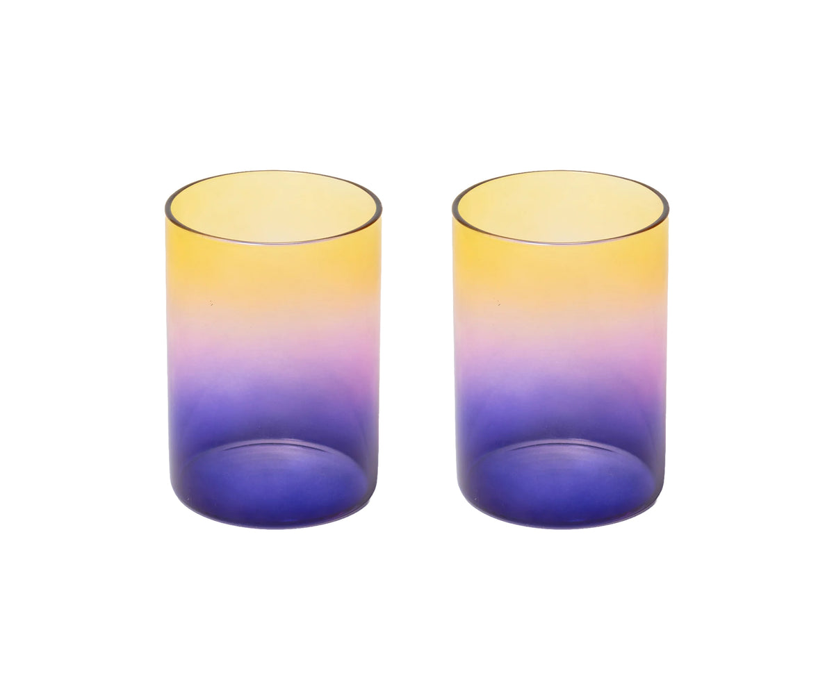 Two cylindrical gradient tumblers with a yellow-to-purple-to-blue ombre design, shown side-by-side on a white background.