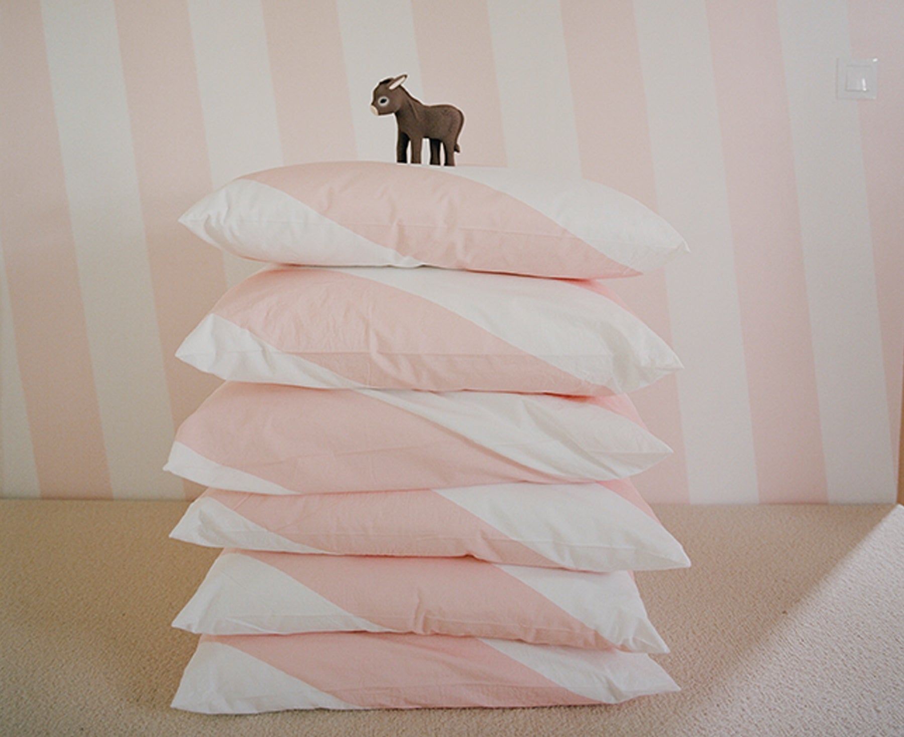 Hector the Donkey Chewable Toy by Oli & Carol on pink and white pillows.