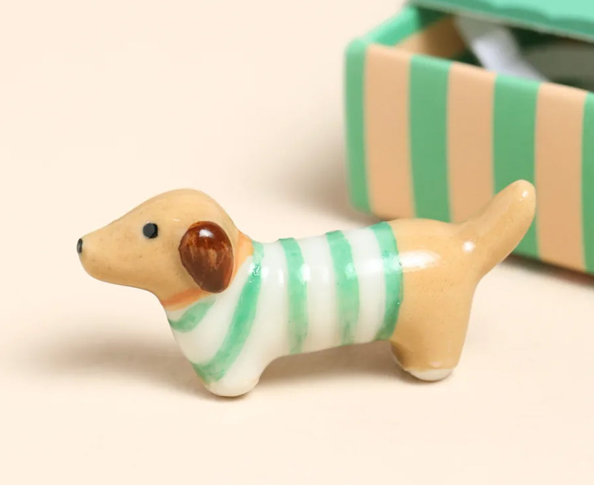Tiny Ceramic Sausage Dog by Lisa Angel outside a striped green box