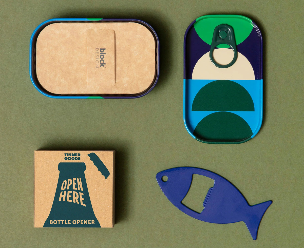 A styled flat-lay of a tinned goods packaging set on an olive green background, including a rectangular tin with a kraft paper lid, a can-shaped pull-tab container, a small box labeled &