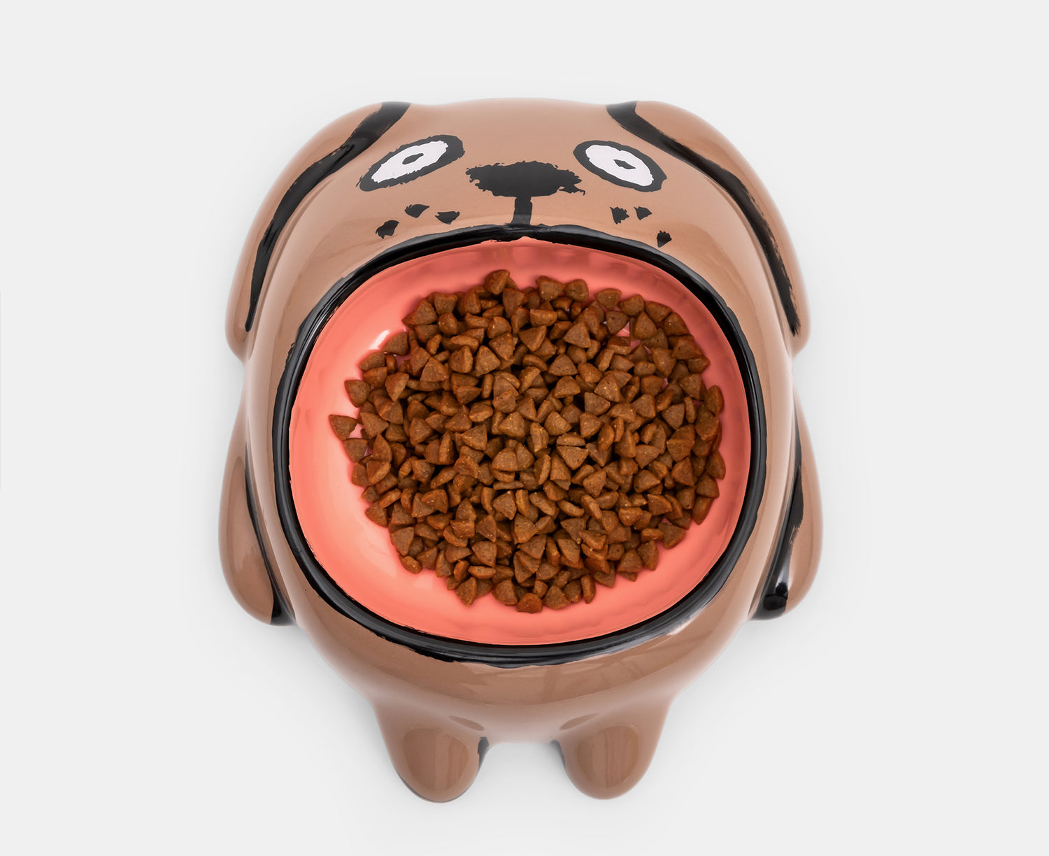 A ceramic Dog Bowl by Home Studyo with a brown body, black hand-drawn facial features, and a large glossy peach opening.