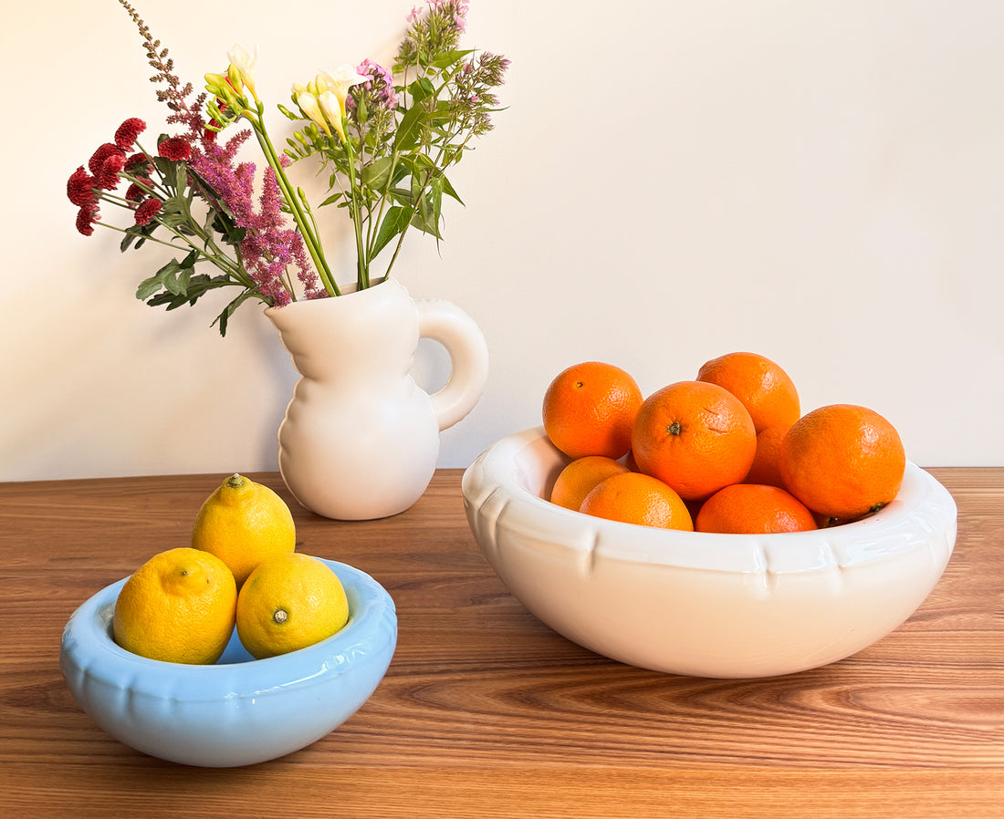 Three ceramic Blow Up items in light blue, white, and off-white on a wooden table.