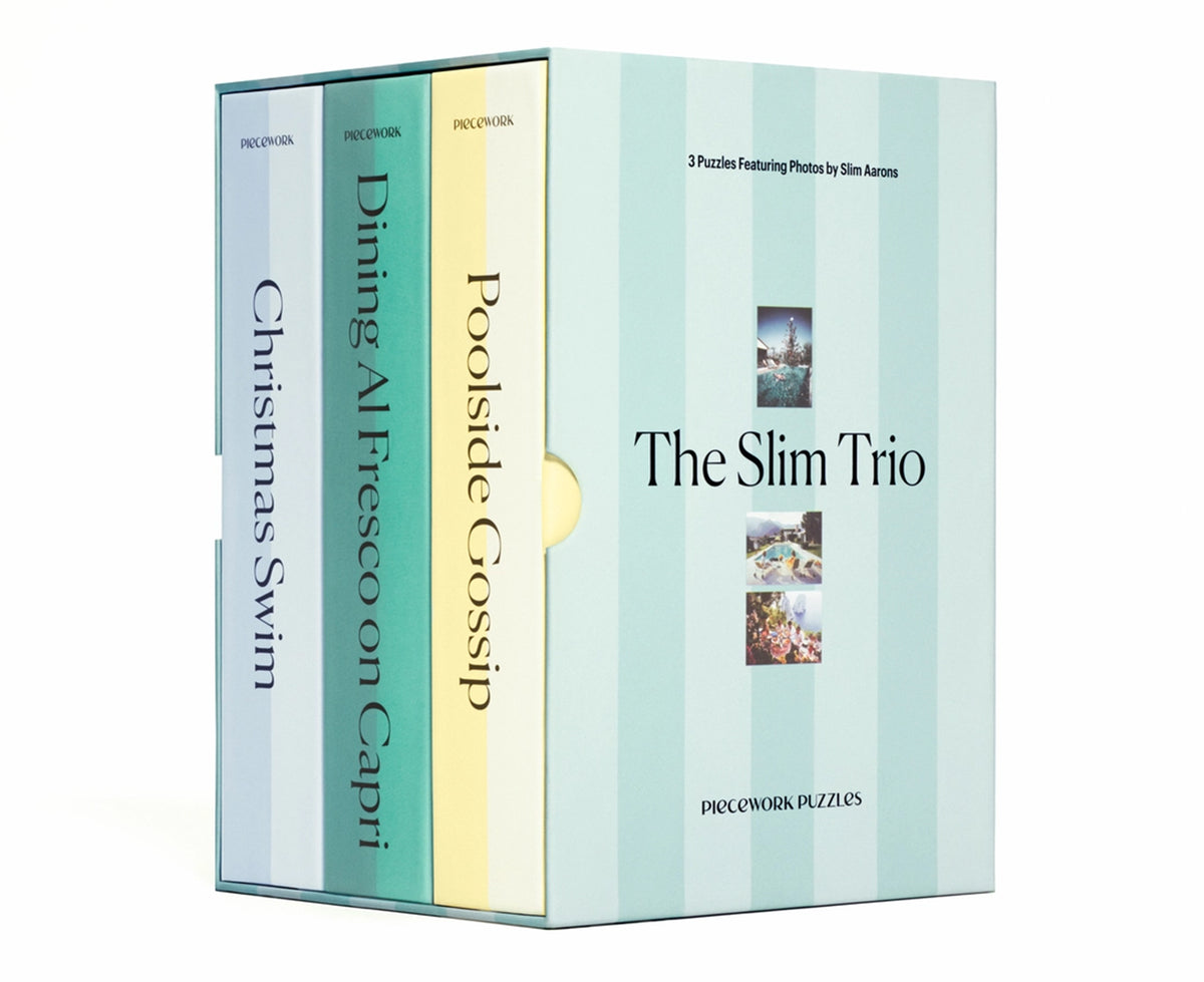 A boxed puzzle book set titled "The Slim Trio" with three slim volumes standing behind a matching cover. The spines are labeled Christmas Swim, Dining At Fresco on Capri, and Poolside Gossip, and the front cover shows small scenic photos.