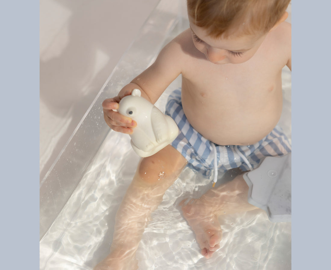 Child playing with a white polar bear chewable toy with Oli &amp; Carol branding.