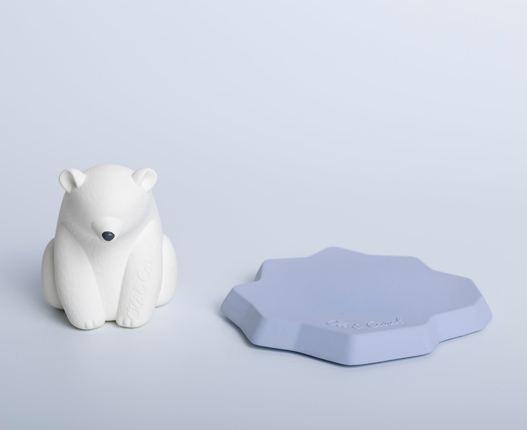 White polar bear chewable toy on a blue base of ice with Oli &amp; Carol branding.