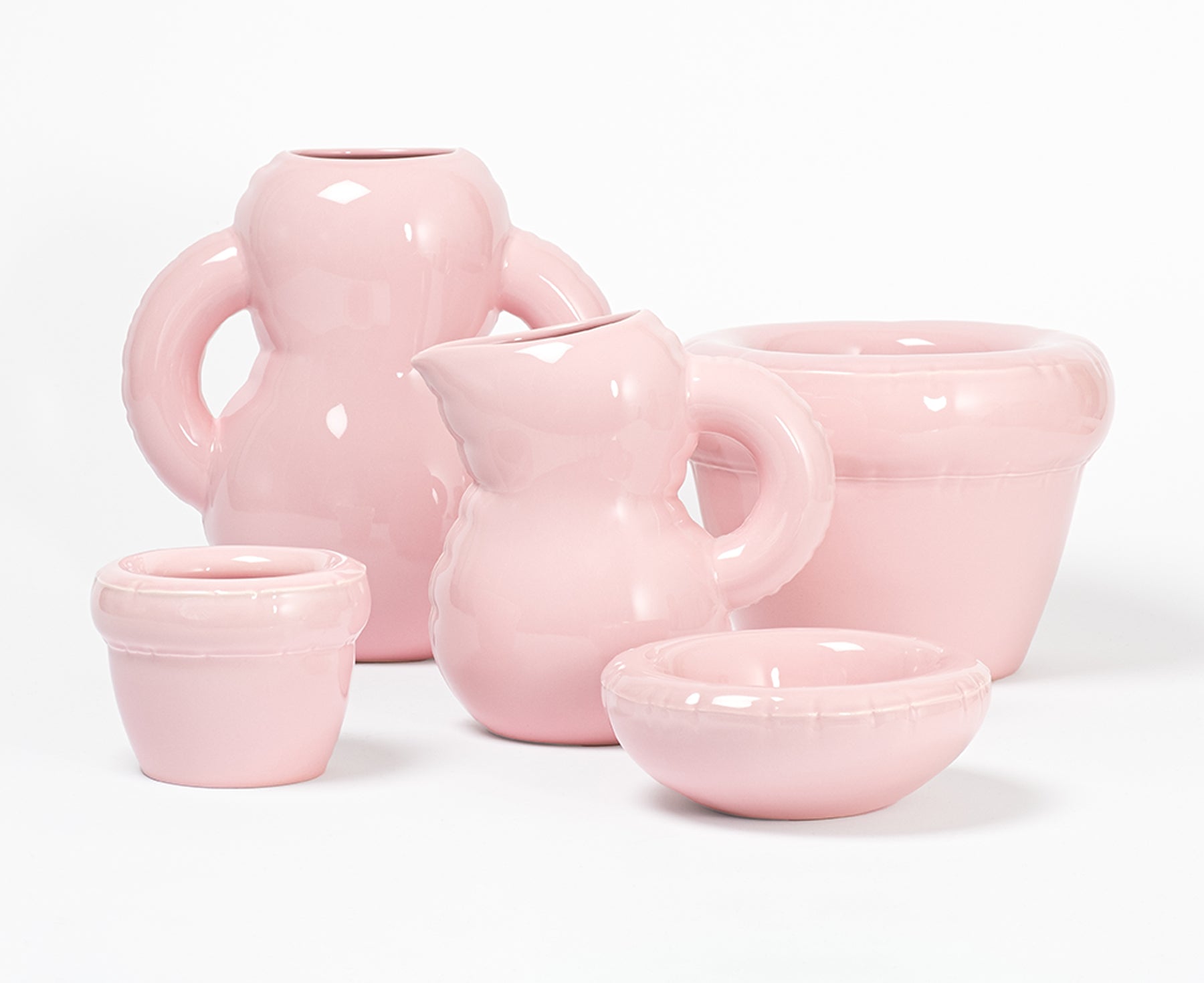 Multiple pieces of the Blow Up ceramic collection in Bubblegum pink by Home Studyo with rounded bodies and a gloss finish.