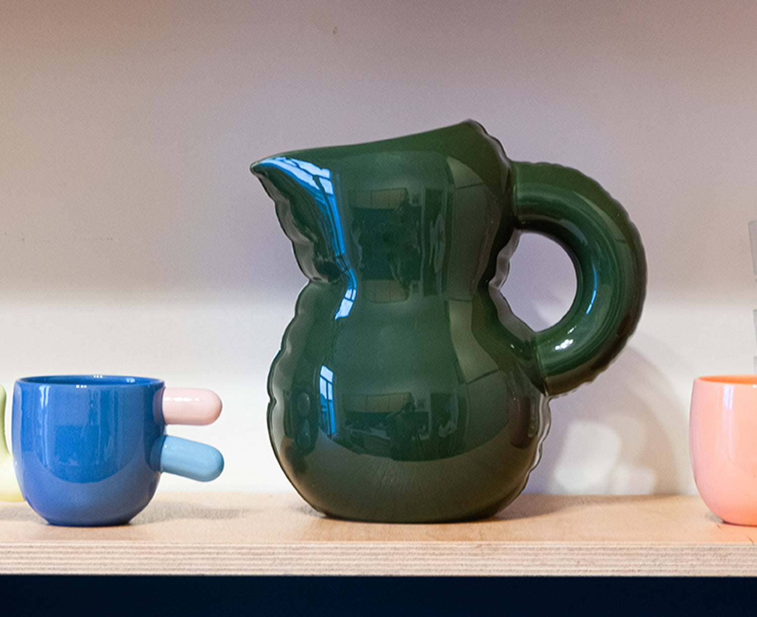 Emily Blow Up ceramic Jug in Moss Green by Home Studyo with a rounded body, ribbed texture, and a curved handle on a shelf.