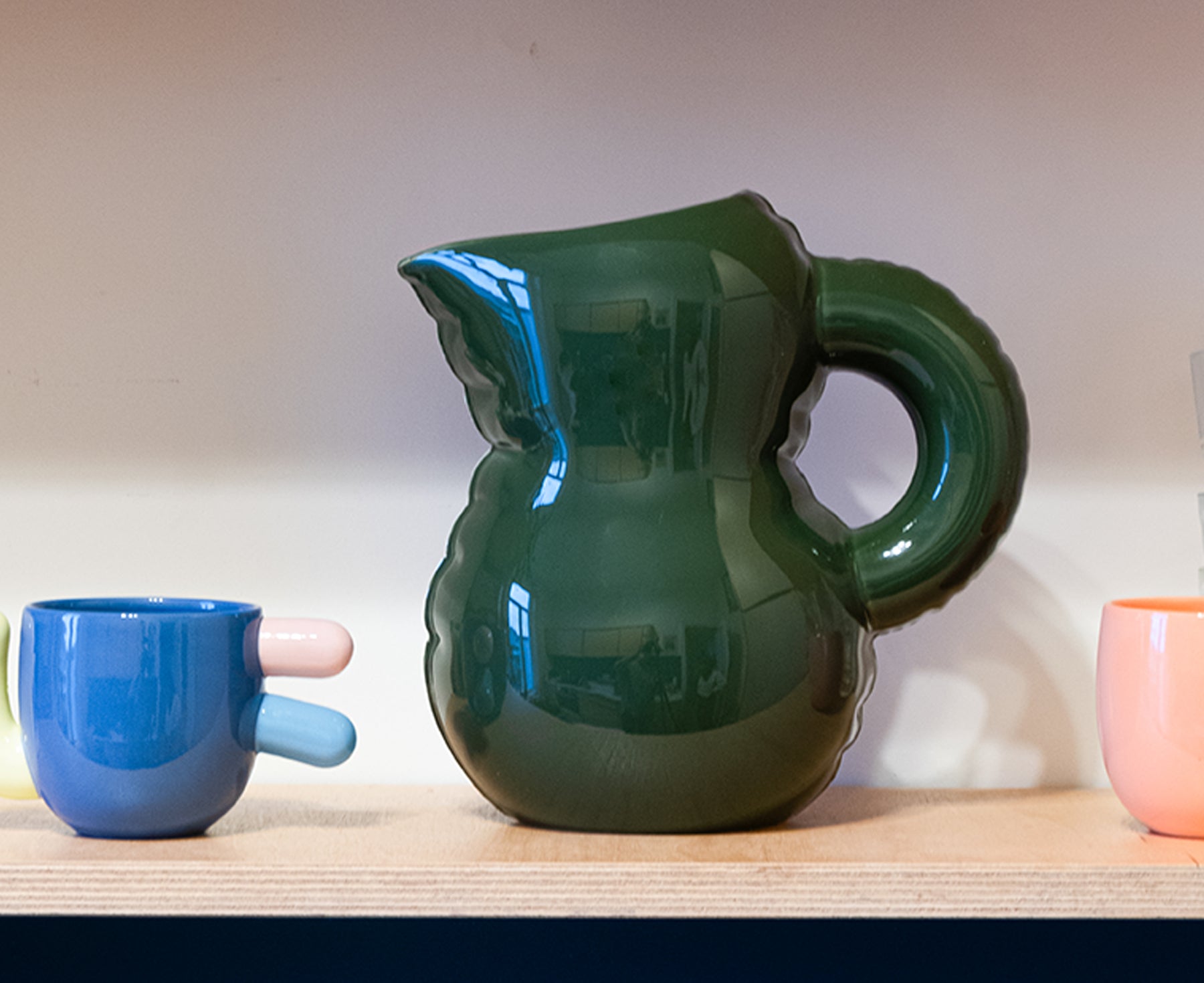 Emily Blow Up ceramic Jug in Moss Green by Home Studyo with a rounded body, ribbed texture, and a curved handle on a shelf.