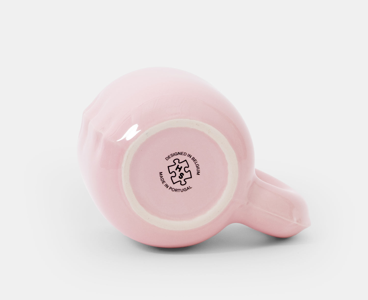 The bottom of a glossy pink ceramic Gaston Blow Up Mug by Home Studyo with a sculpted, organic handle and side details.
