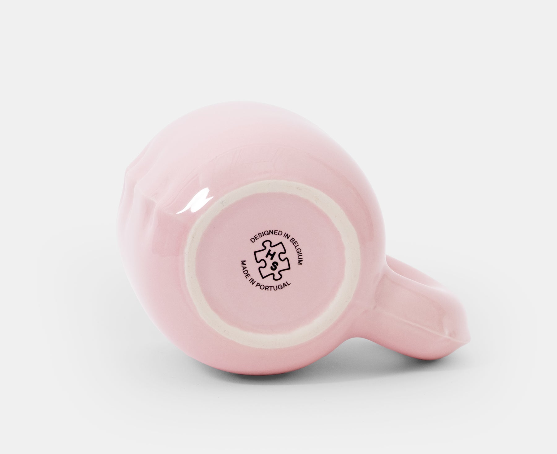 The bottom of a glossy pink ceramic Gaston Blow Up Mug by Home Studyo with a sculpted, organic handle and side details.