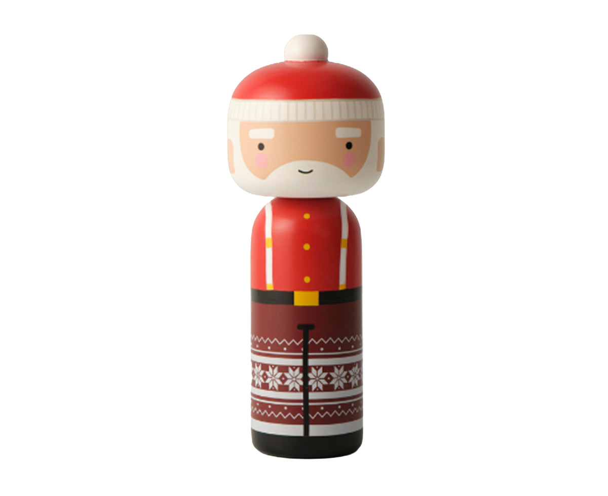 A Santa Claus-themed wooden kokeshi doll with a red hat, white beard, red jacket with yellow buttons, and a brown patterned skirt with white snowflakes, isolated on a white background.
