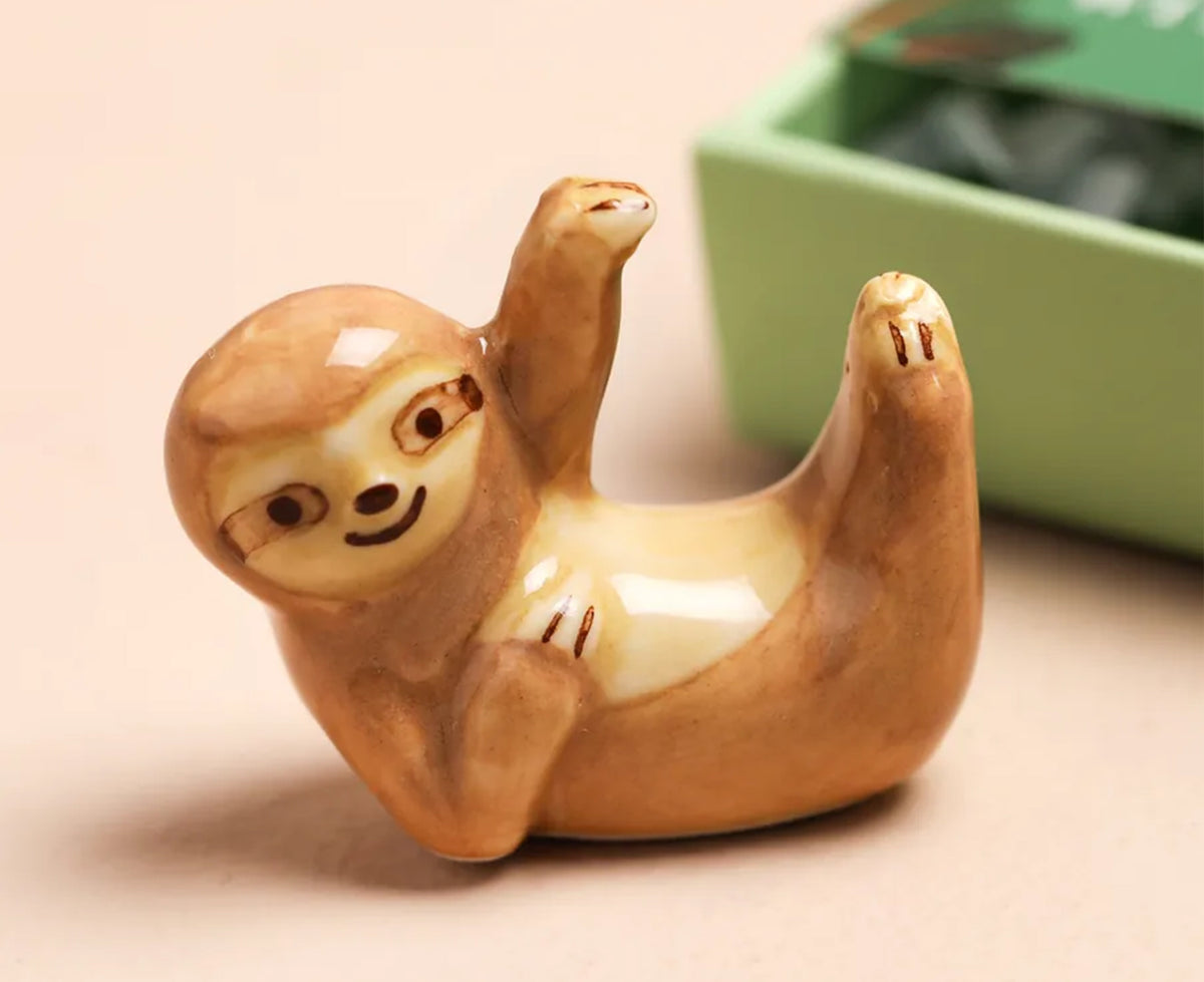 mini ceramic sloth on a beige background.