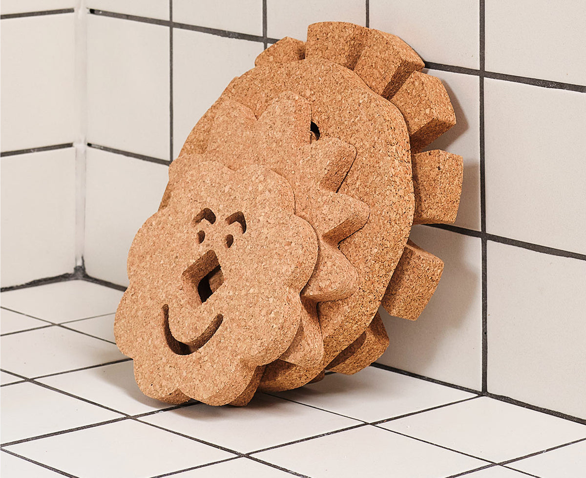 Several shaped cork trivets by Wrap leaaning against a wall on a kitchen counter.