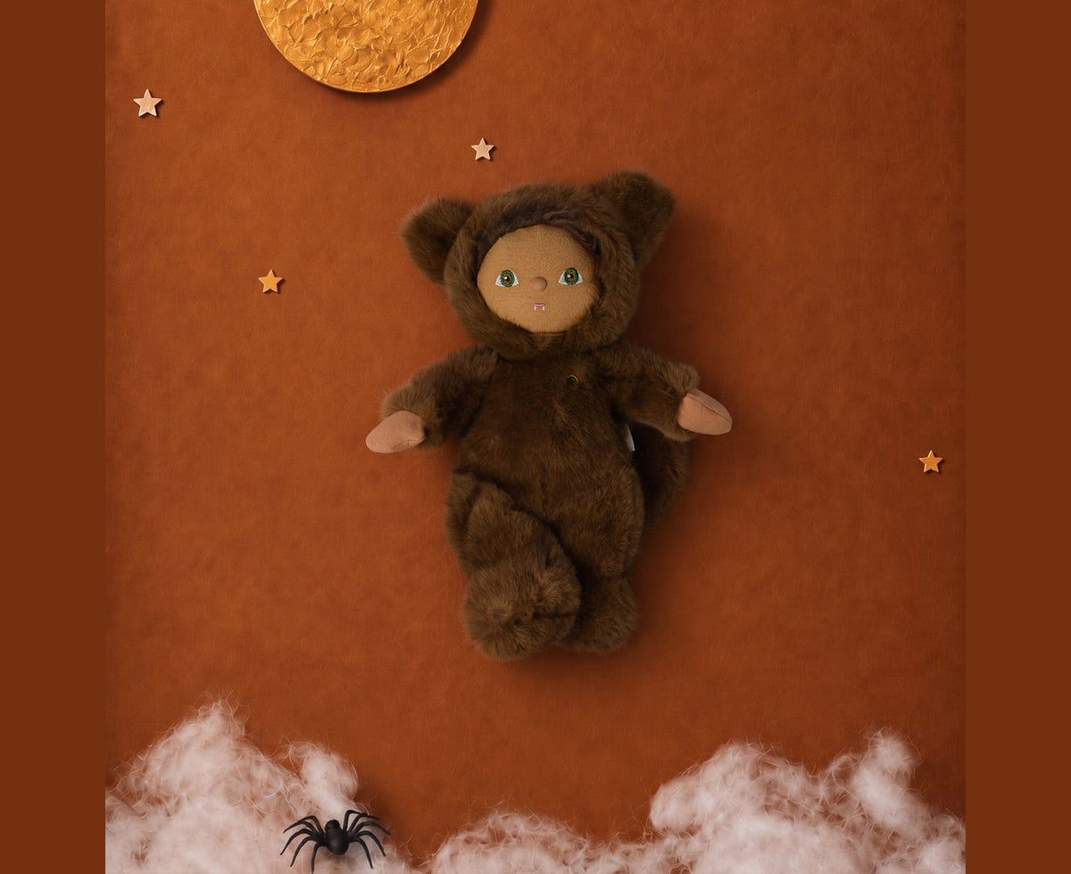 A plush werewolf cozy dinkum doll wearing a brown hooded outfit with floppy ears shown against an orange background with clouds and a moon and stars.
